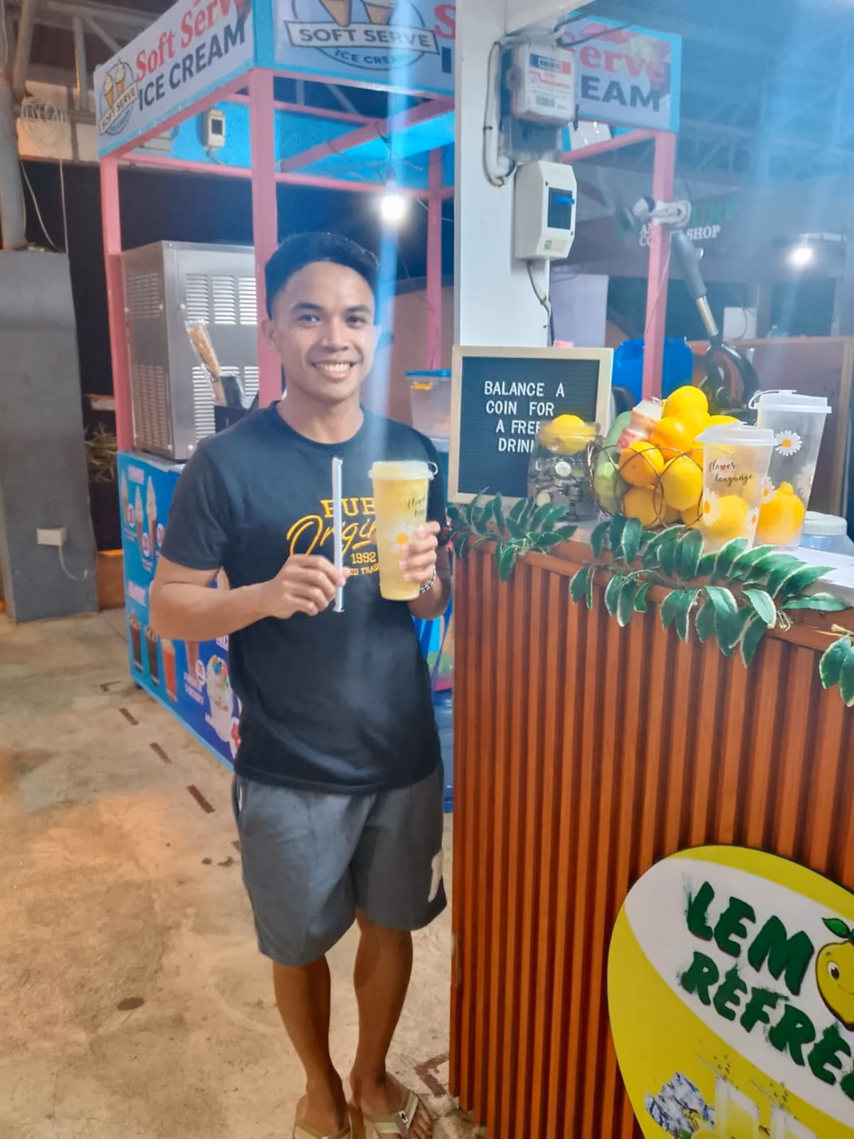 A customer holding a Lemon Refresh drink in front of the lemon-decorated cart