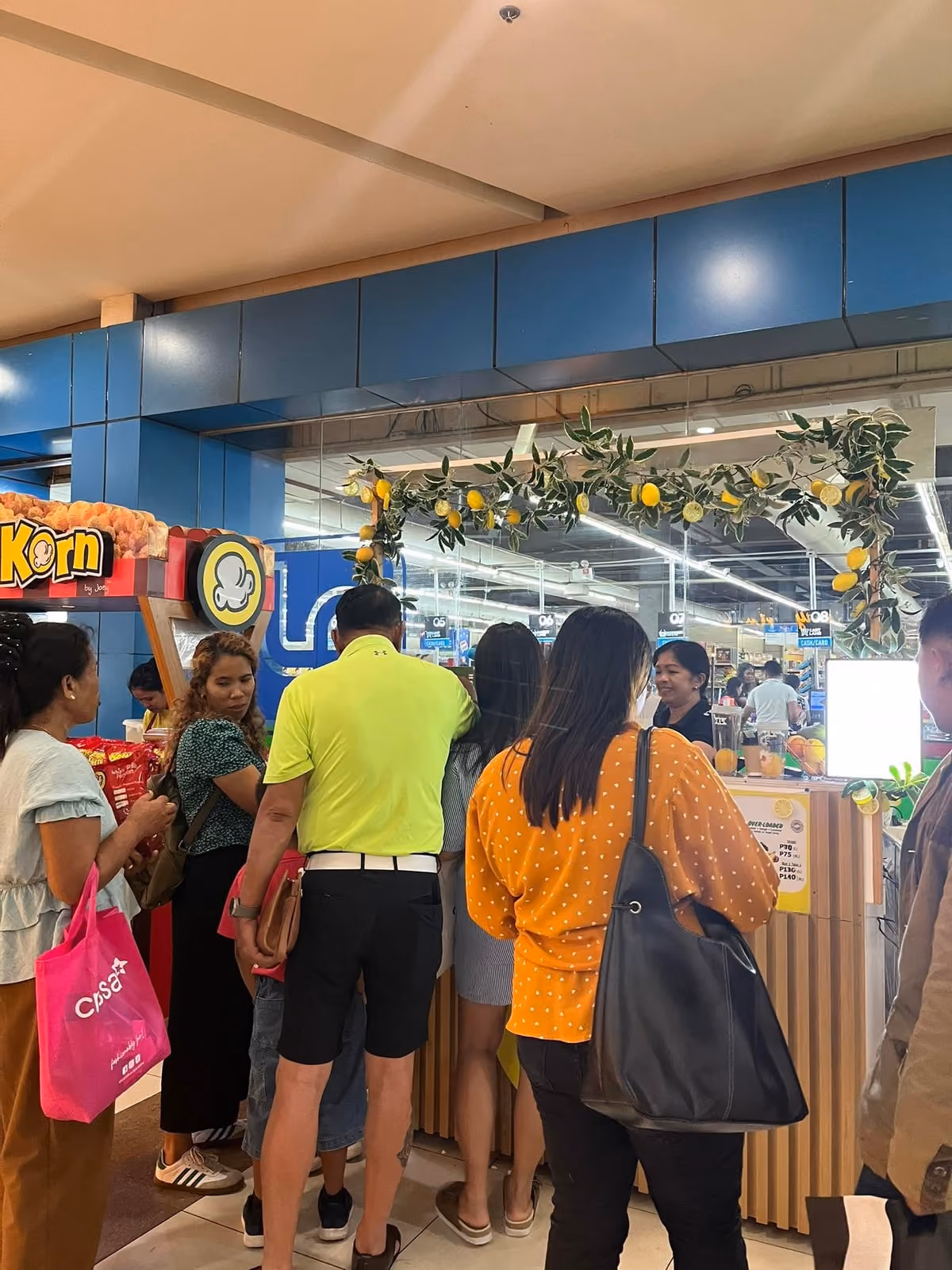 The Lemon Refresh stall inside a mall, decorated with a garland of lemons and foliage, with customers at the counter